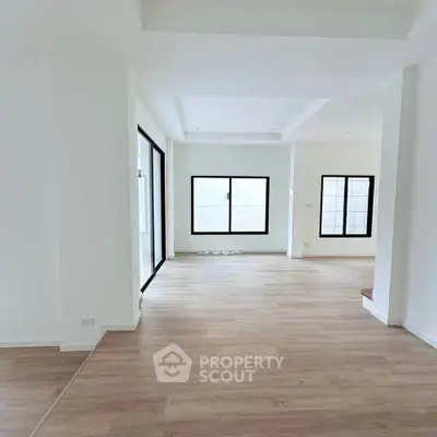 Spacious modern living room with wooden flooring and large windows for natural light.