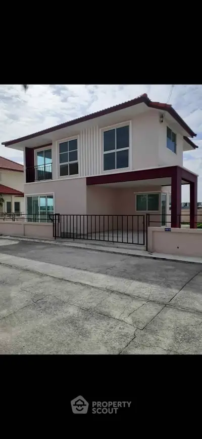 Modern two-story house with large windows and gated entrance in a suburban neighborhood.