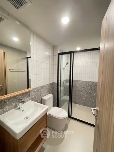 Modern bathroom with sleek design, featuring a glass-enclosed shower and stylish vanity.