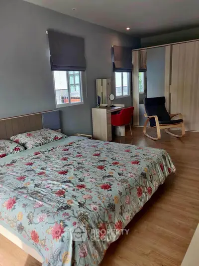 Spacious bedroom with floral bedding and modern furniture, ideal for comfort and style.