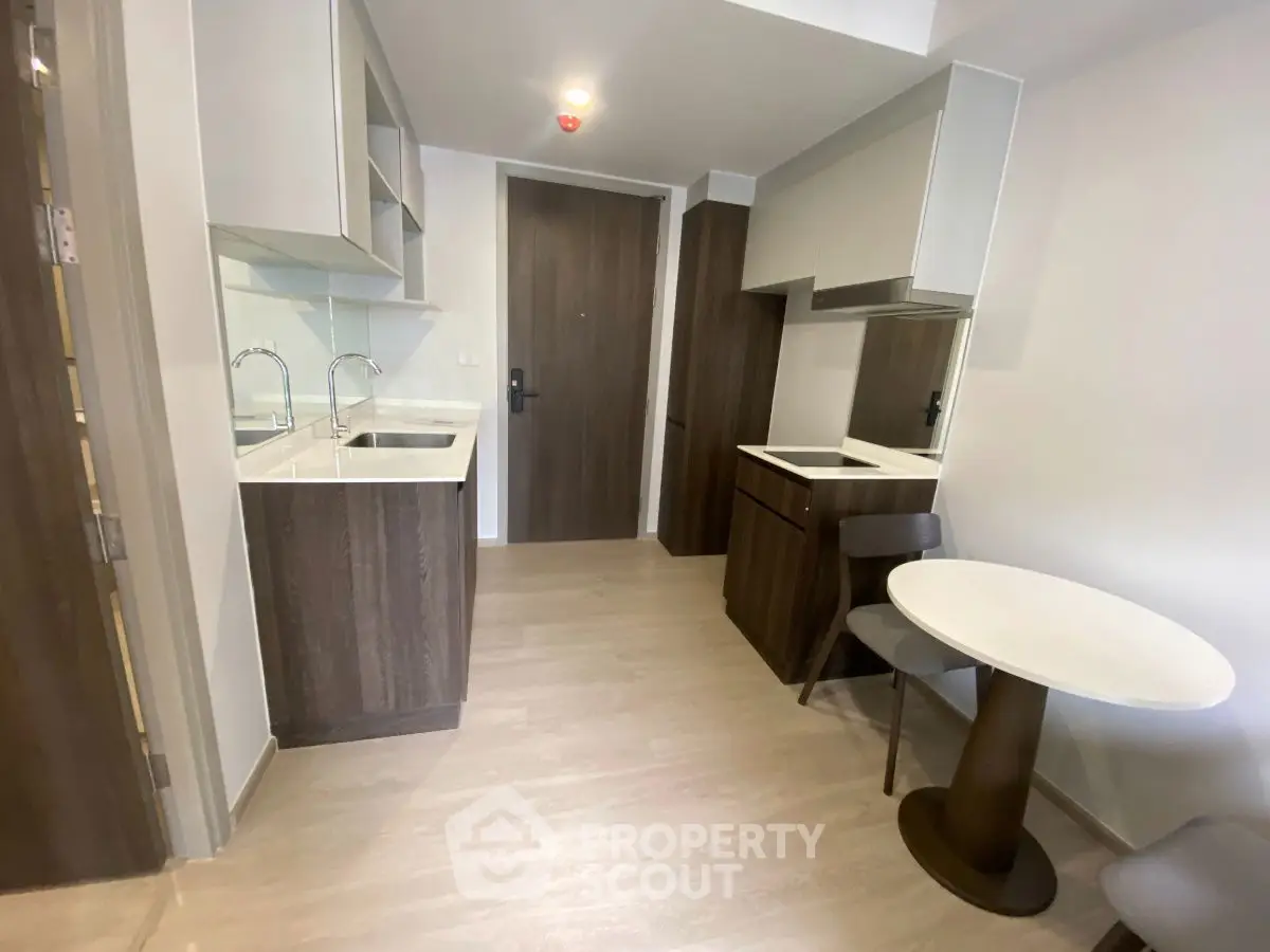 Modern compact kitchen with sleek cabinetry and dining area in a stylish apartment.