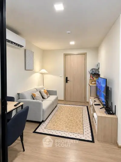 Modern living room with cozy sofa and TV, featuring stylish decor and wooden flooring.