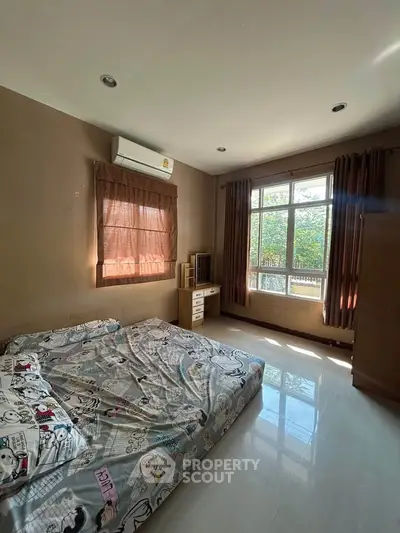 Cozy bedroom with large window and natural light, featuring air conditioning and modern furnishings.