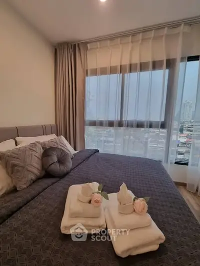 Cozy bedroom with elegant decor and city view, featuring plush bedding and soft lighting.