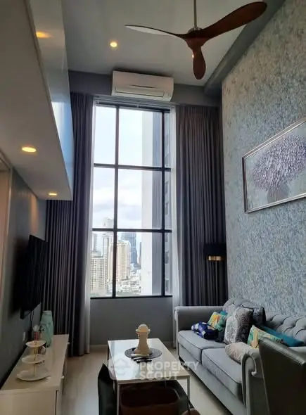 Modern living room with high ceiling and city view, featuring stylish decor and large window.