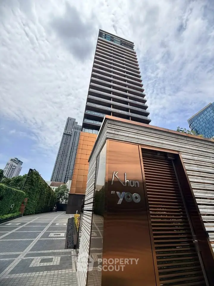 Stunning modern high-rise building with sleek design and luxurious entrance in urban setting.