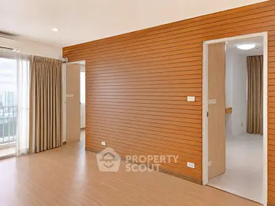 Spacious modern living room with wooden panel walls and large windows offering city views.
