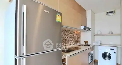 Modern kitchen with stainless steel fridge and washing machine in sleek apartment.