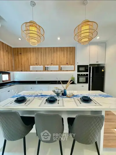 Modern kitchen with island, stylish lighting, and elegant dining setup in a contemporary home.
