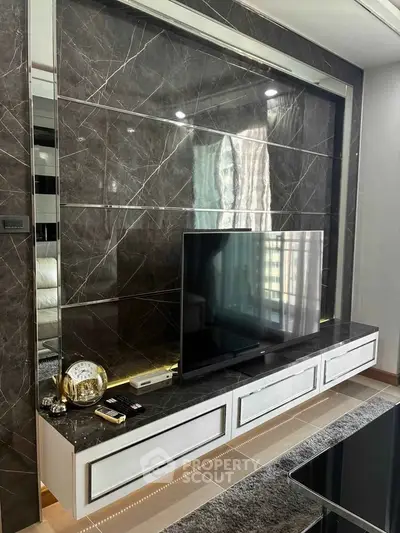 Luxurious living room with modern TV setup and elegant marble wall design.