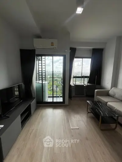 Modern living room with balcony and scenic view, featuring sleek furniture and natural light.