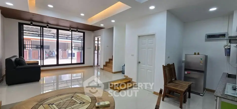 Modern living room with stylish decor and open layout, featuring a cozy seating area and sleek kitchen appliances.