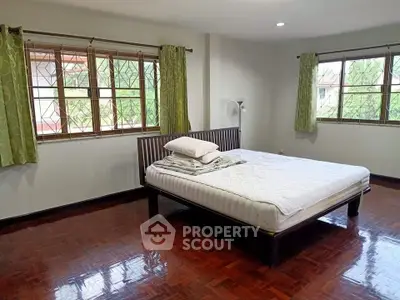 Spacious bedroom with large windows and wooden flooring