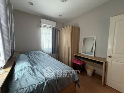Cozy bedroom with natural light, featuring a bed, wardrobe, and a vanity mirror, perfect for relaxation.