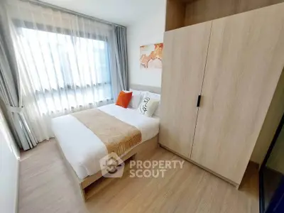 Bright and cozy bedroom with large window and modern wardrobe, perfect for relaxation.