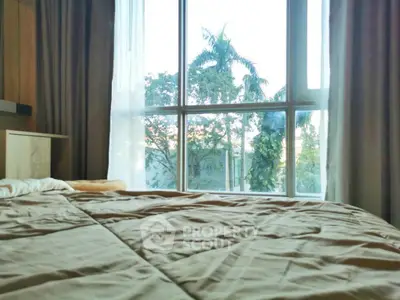 Cozy bedroom with large window offering lush garden view