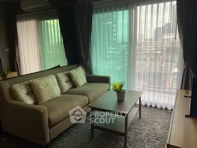 Cozy living room with large windows and city view, featuring a comfortable sofa and stylish decor.