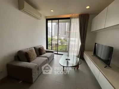 Modern living room with city view, featuring a sleek sofa and glass coffee table.
