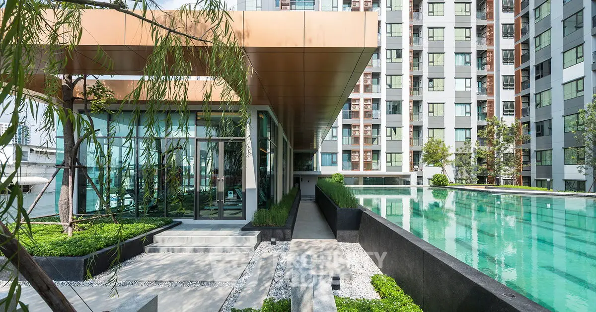 Modern apartment building with sleek poolside area and lush greenery.