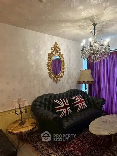 Elegant living room with vintage decor, featuring a classic chandelier, ornate mirror, and plush sofa.