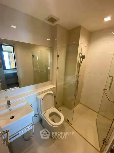 Modern bathroom with glass shower and sleek fixtures in a contemporary apartment.
