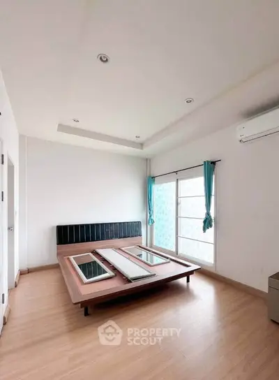 Spacious bedroom with modern bed frame and large windows for natural light.