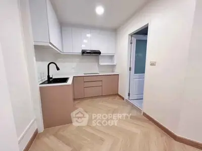 Modern kitchen with sleek cabinetry and herringbone flooring in a stylish apartment.