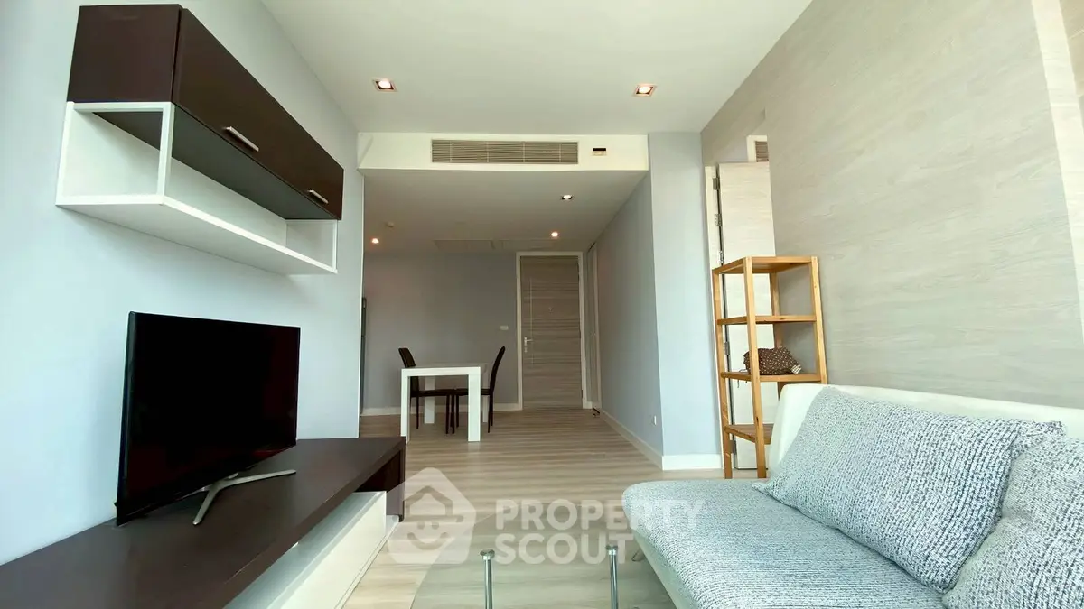 Modern living room with sleek furniture and neutral tones, featuring a wall-mounted TV and stylish shelving.