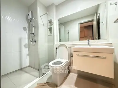 Modern bathroom with glass shower and sleek vanity in contemporary apartment.