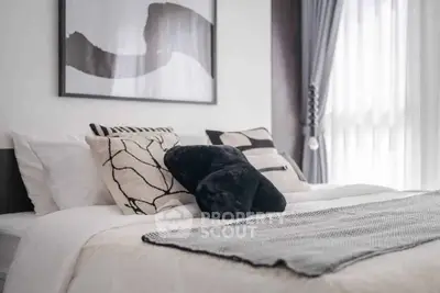 Modern bedroom with stylish decor and natural light, featuring elegant pillows and contemporary artwork.