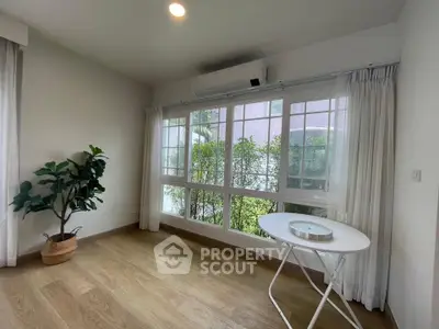 Bright and airy room with large windows and wooden flooring, perfect for a cozy living space.