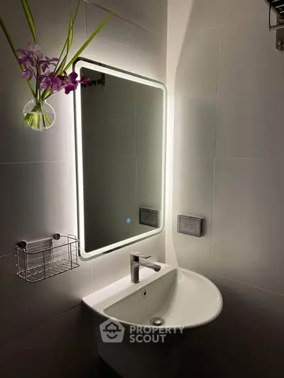 Modern bathroom with illuminated mirror and sleek sink design.