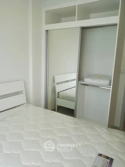 Modern bedroom with white furniture and built-in closet, perfect for minimalist living.