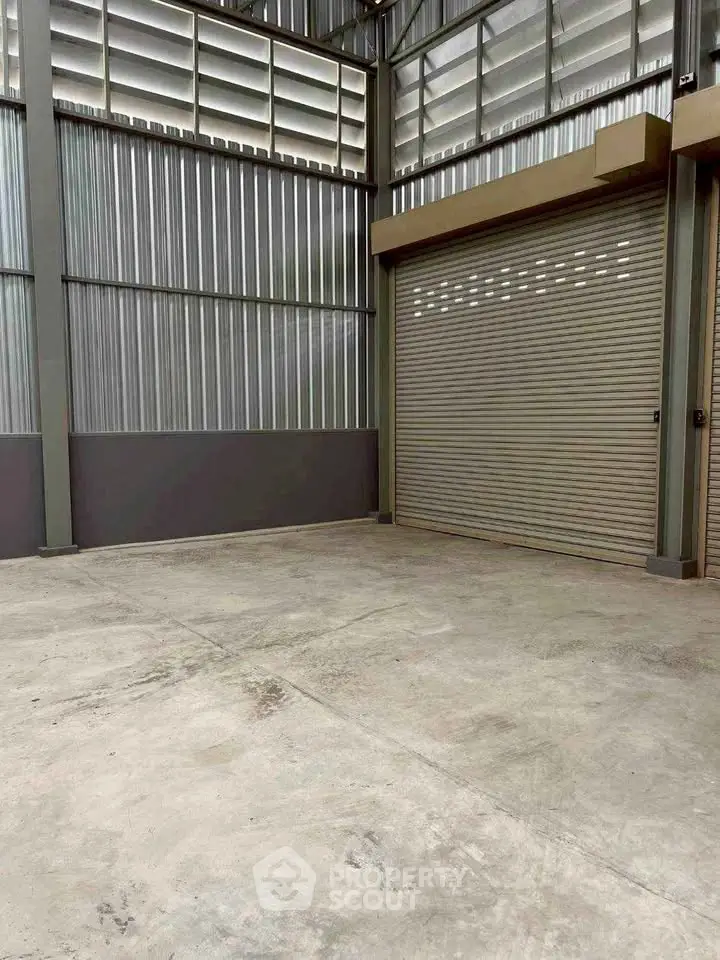 Spacious industrial warehouse with high ceilings and large roller door access.