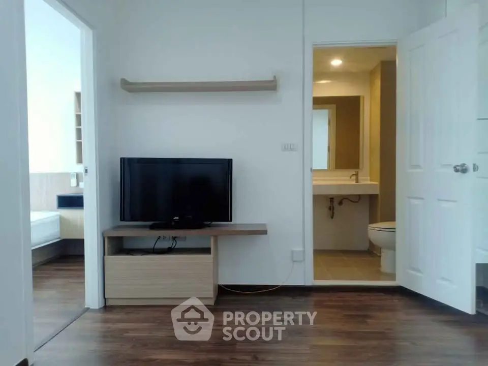 Modern apartment with open living area and bathroom, featuring sleek wooden flooring and minimalist design.