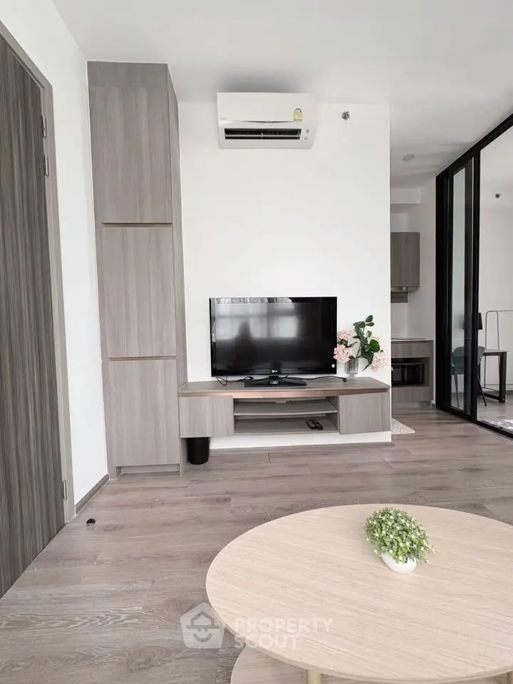 Modern living room with sleek furniture and air conditioning, featuring a flat-screen TV and stylish decor.