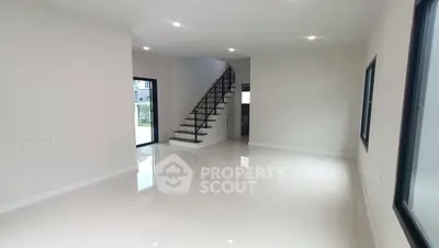Spacious modern living room with sleek staircase and large windows.