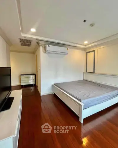 Spacious bedroom with wooden flooring and modern air conditioning unit