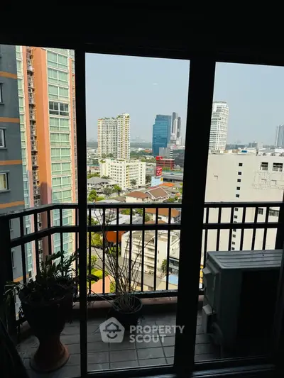 Stunning city view from a high-rise balcony with modern railing and potted plants.
