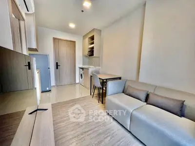 Modern living room with sleek furniture and integrated kitchen appliances in a cozy apartment.