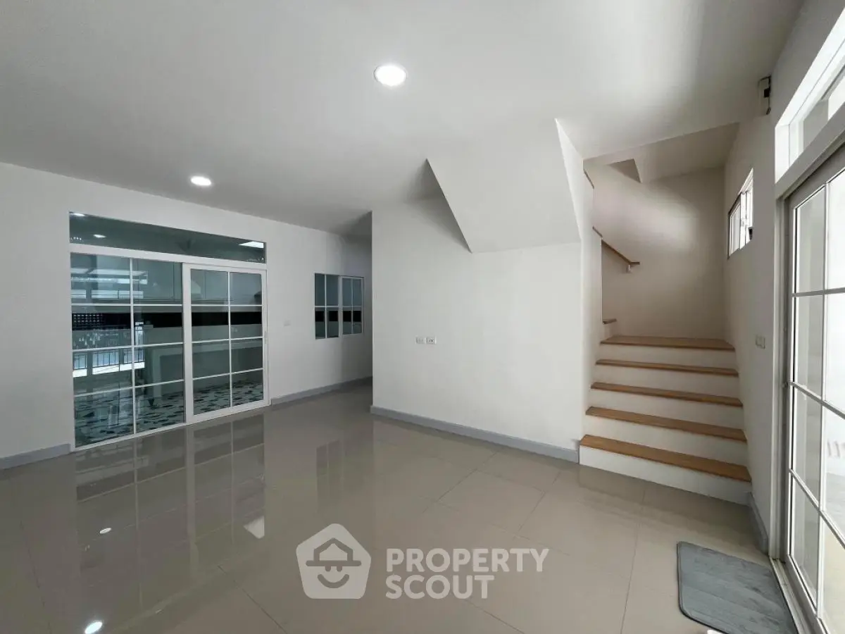 Spacious modern living room with sleek staircase and glossy tiled floors