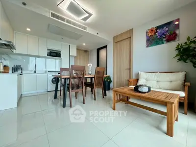 Modern open-plan living room with kitchen, dining area, and stylish decor in a bright apartment.
