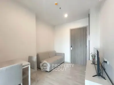 Modern living room with minimalist decor and neutral tones, featuring a cozy sofa and sleek TV setup.