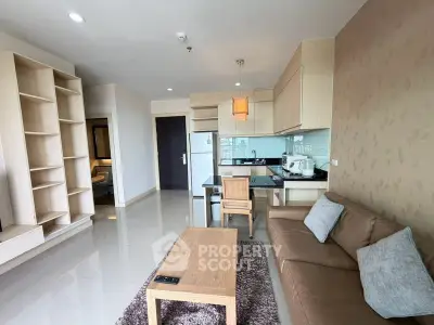 Modern living room with open kitchen, featuring sleek furniture and ample natural light.