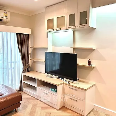 Modern living room with sleek TV unit and stylish shelving, featuring natural light and elegant decor.