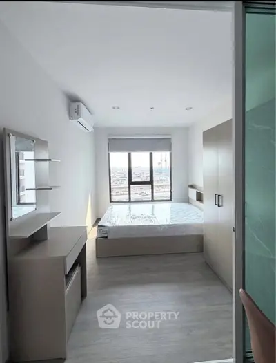 Modern bedroom with large window and sleek furniture in a stylish apartment.