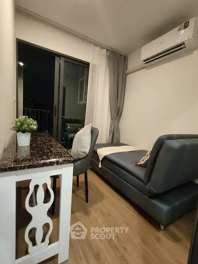 Cozy modern living room with sleek furniture and air conditioning, featuring a small balcony view.