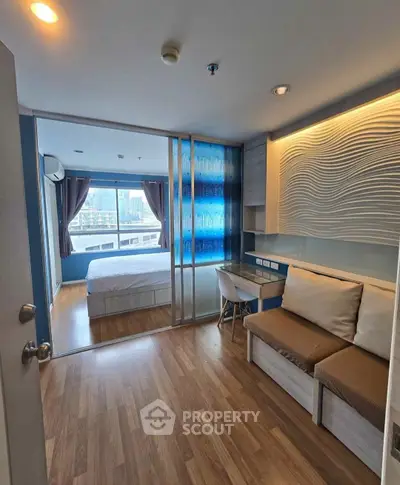 Modern studio apartment with sliding glass doors and city view, featuring cozy seating and stylish decor.