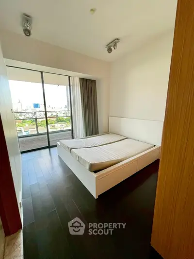 Spacious bedroom with city view and large windows in modern apartment.