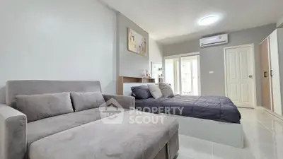 Modern bedroom with stylish decor and natural light, featuring a cozy bed and elegant sofa.